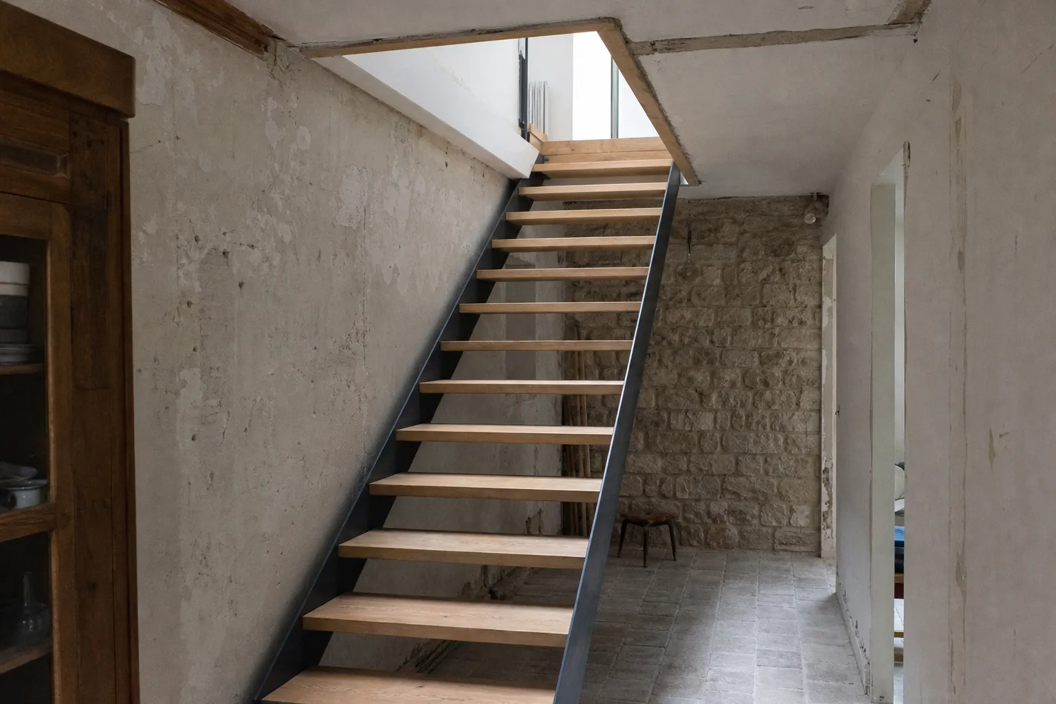 Escalier droit neuf montant vers des combles aménagés, limon acier et marches de chêne, trémie découpée dans un plafond ancien