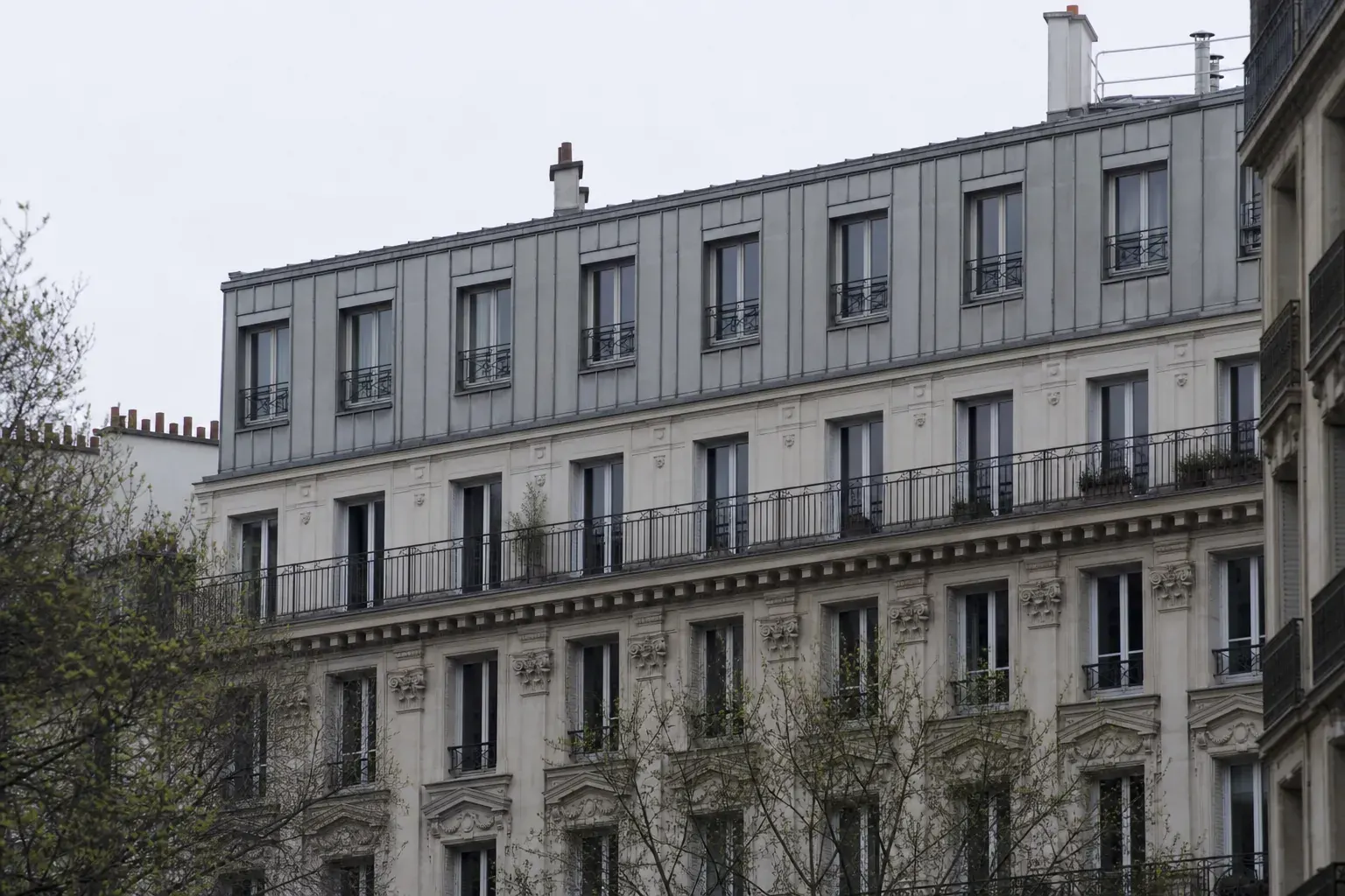 Étage supplémentaire en zinc à joint debout posé au-dessus de la corniche d’un immeuble parisien, garde-corps en acier sombre